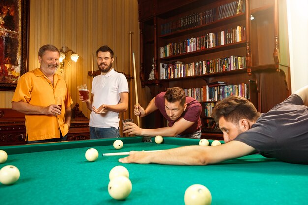 Nahaufnahme eines Mannes, der Billard spielt. kaukasisches Modell, das sorgfältig und anstrengend mit dem Stichwort im Ball zielt. Spielkonzept