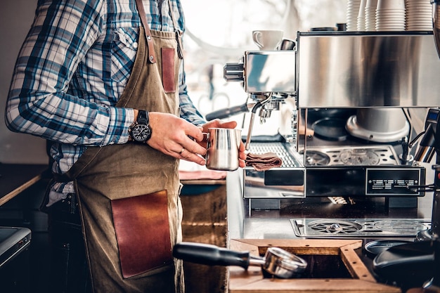 Nahaufnahme eines Mannes, der Cappuccino in einer Kaffeemaschine zubereitet.