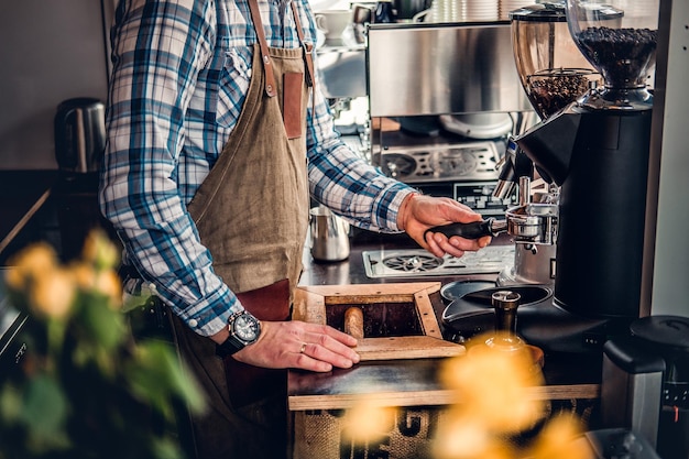 Kostenloses Foto nahaufnahme eines mannes, der cappuccino in einer kaffeemaschine zubereitet.