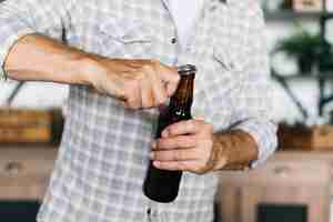 Kostenloses Foto nahaufnahme eines mannes, der die bierflasche mit öffner öffnet