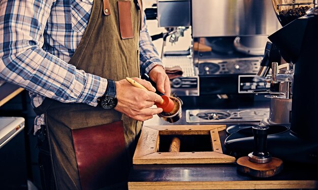 Nahaufnahme eines Mannes, der die Kaffeemaschine mit einer Quaste reinigt.