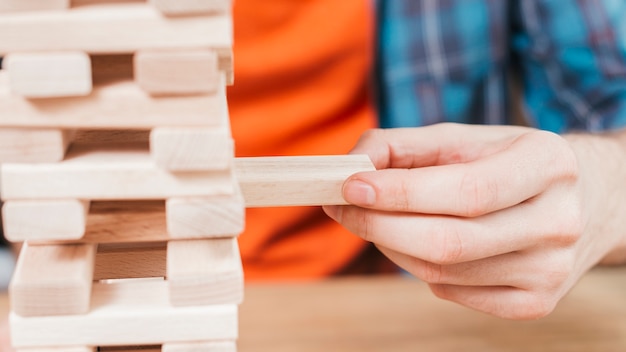 Nahaufnahme eines Mannes, der Holzklotzturmspiel spielt