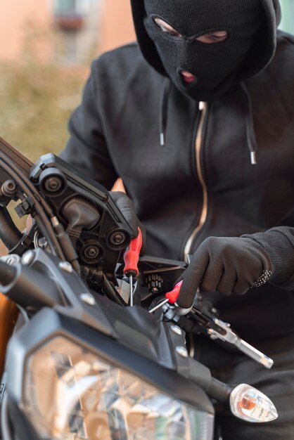 Nahaufnahme eines Mannes, der sich darauf vorbereitet, ein Motorrad zu stehlen