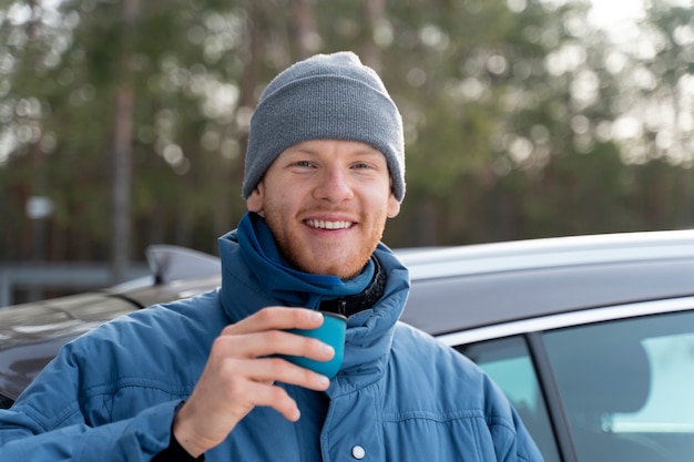 Nahaufnahme eines Mannes, der während einer Winterreise ein heißes Getränk genießt