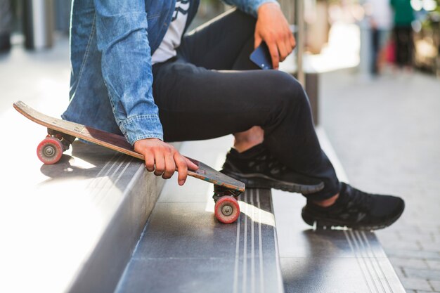 Nahaufnahme eines Mannes mit dem Skateboard, das auf Treppenhaus sitzt