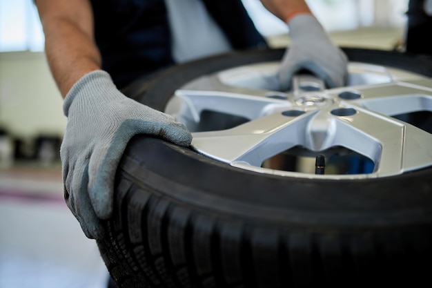 Kostenloses Foto nahaufnahme eines mechanikers, der mit autoreifen in der autowerkstatt arbeitet