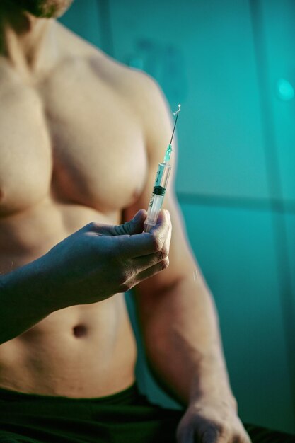 Nahaufnahme eines muskulösen Mannes mit Injektion von anabolen Steroiden in der Umkleidekabine des Fitnessstudios