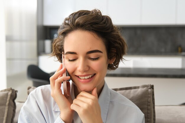 Nahaufnahme eines Porträts einer lächelnden schönen Frau, die über Handy-Chats spricht und auf dem Smartphone jemanden anruft