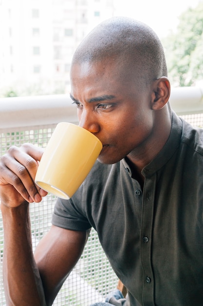 Nahaufnahme eines rasierten jungen afrikanischen Mannes, der den Kaffee trinkt