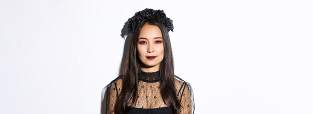 Nahaufnahme eines schönen gotischen Mädchens mit schwarzem Kranz, das sich für die Halloween-Party anzieht, die über steht