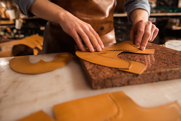 Nahaufnahme eines Schuhmachers, der Leder misst