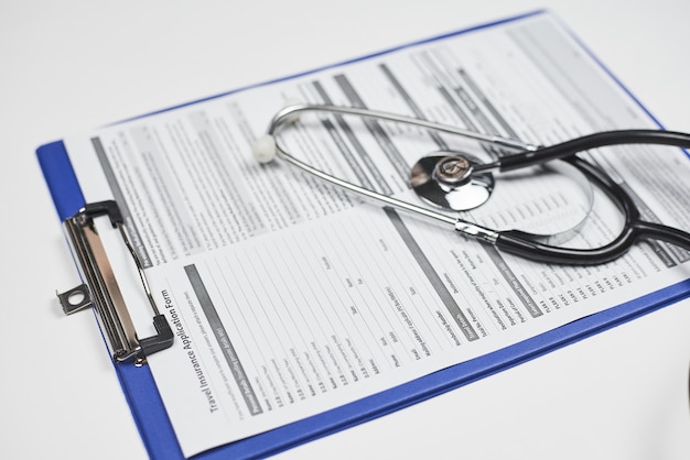 Nahaufnahme eines Stethoskops auf einem Antragsdokument für eine Reiseversicherung
