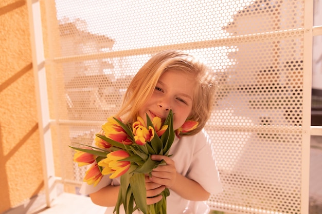 Nahaufnahme eines süßen jungen Mädchens mit Blumen, das in die Kamera lächelt