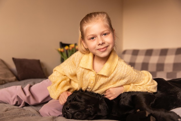 Nahaufnahme eines süßen Mädchens, das mit einem Hundeblick auf die Kamera auf dem Bett sitzt