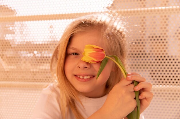 Nahaufnahme eines süßen, süßen jungen Mädchens mit Blumen, das in die Kamera lächelt