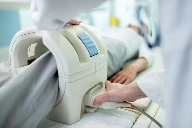 Nahaufnahme eines Technikers, der einen Patienten für das Knie-MRT-Scan-Verfahren in der Klinik vorbereitet