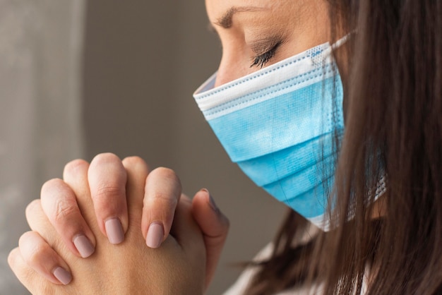 Nahaufnahme erwachsene Frau mit chirurgischer Maske beten