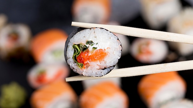 Nahaufnahme Essstäbchen mit Sushi-Rolle
