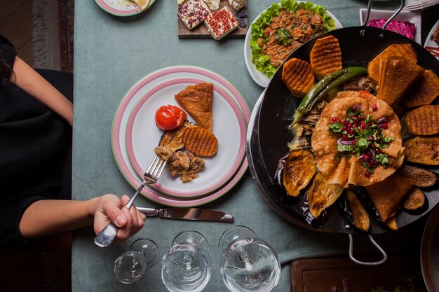 Nahaufnahme Fleisch mit Ofenkartoffeln, Auberginen, Tomaten, Pfeffer und mit Granatapfel in einem Teller auf Serviertisch dekoriert