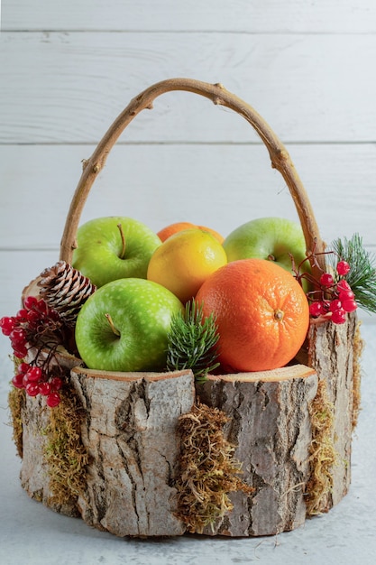 Nahaufnahme Foto Holzkorb voll mit verschiedenen Früchten auf grauer Oberfläche.