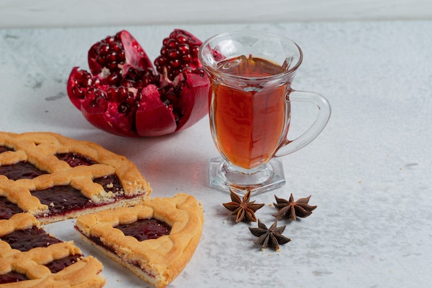 Nahaufnahme Foto von hausgemachtem Obstkuchen mit Tee und geschnittenem Granatapfel.