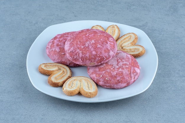 Nahaufnahme Foto von hausgemachten rosa Cookies auf weißer Keramikplatte.