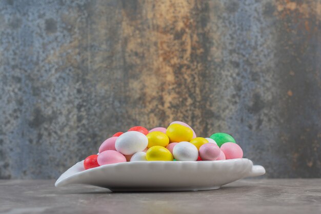 Nahaufnahme foto von runden bunten bonbons auf weißem teller.