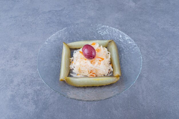 Nahaufnahme Foto von Sauerkraut mit Gurkenscheiben in Glasplatte.