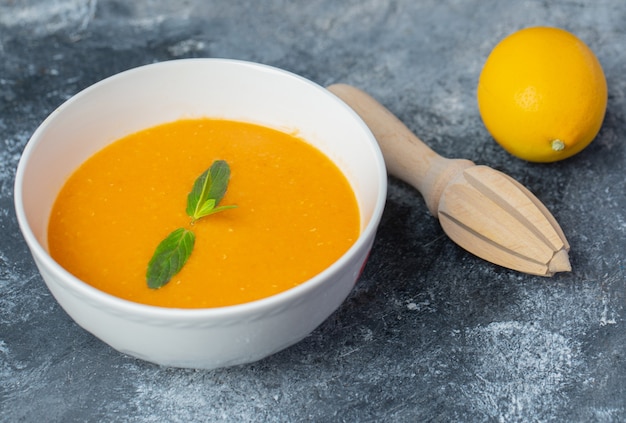 Nahaufnahme Foto von Tomatensuppe und frischer Zitrone mit Zitronenpresse.