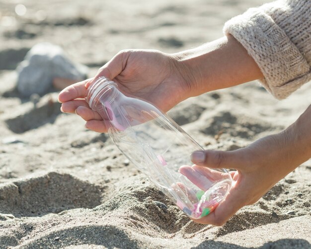 Nahaufnahme Frau, die Sand der Plastikflasche reinigt