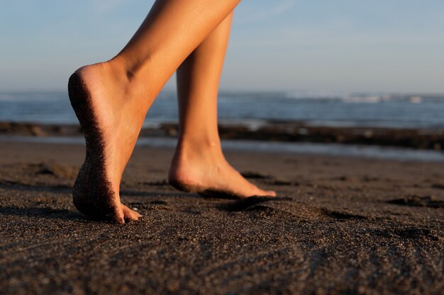 Nahaufnahme. Füße auf schwarzem Sand. bali