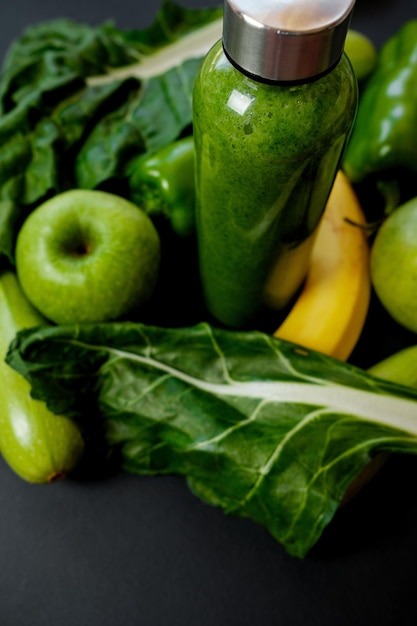 Nahaufnahme Grünes Gemüse und Smoothies in einer Plastikflasche auf schwarzem Hintergrund Gesundes Konzept
