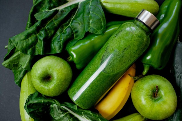 Nahaufnahme Grünes Gemüse und Smoothies in einer Plastikflasche auf schwarzem Hintergrund Gesundes Konzept