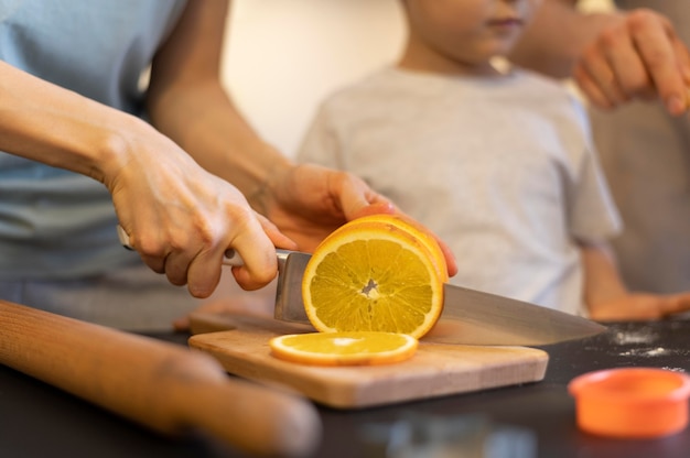 Nahaufnahme Hände, die Orange schneiden