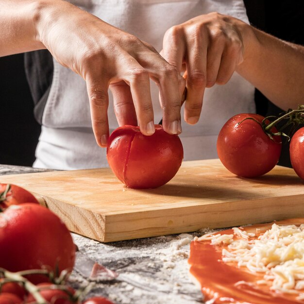 Nahaufnahme Hände, die Tomate schneiden