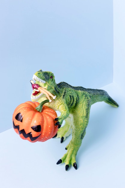 Nahaufnahme Halloween-Dinosaurierspielzeug, das Kürbis hält