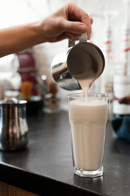 Nahaufnahme Hand, die leckere Milch in Glas gießt