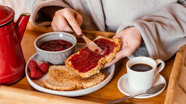 Nahaufnahme Hand, die Marmelade auf Brot setzt