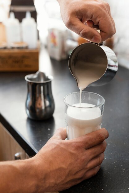 Nahaufnahme Hand, die Milch in Glas gießt