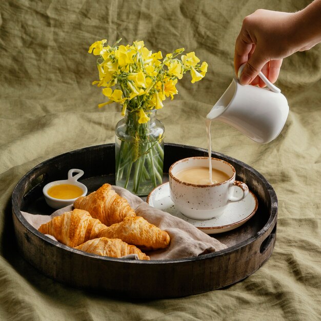 Nahaufnahme Hand, die Milch in Kaffee gießt