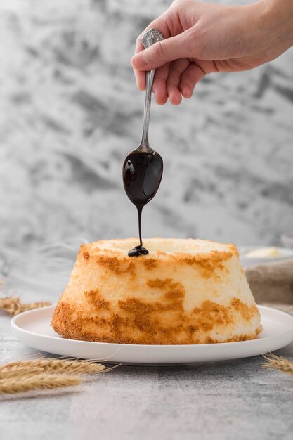 Nahaufnahme Hand, die Schokolade auf hausgemachten Kuchen gießt