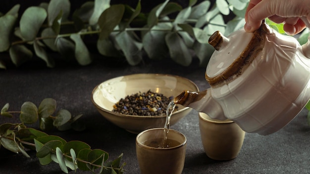 Kostenloses Foto nahaufnahme hand, die tee in tasse gießt