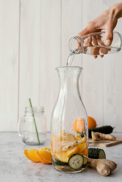 Nahaufnahme Hand, die Wasser in Flasche gießt