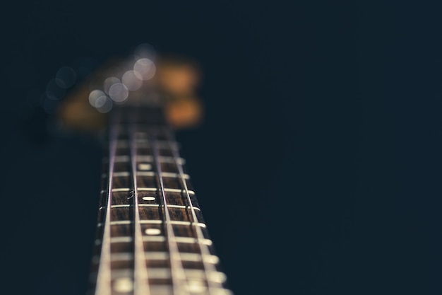 Nahaufnahme im Fokus der Saiten auf einer Bassgitarre auf einem unscharfen schwarzen Hintergrund.