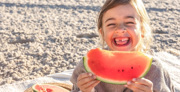 Nahaufnahme kleines Mädchen isst Wassermelone am Strand