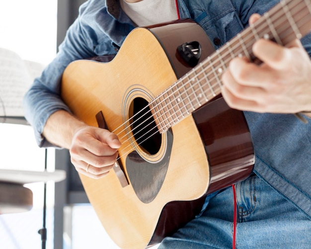 Nahaufnahme Mann, der eine Akustikgitarre hält