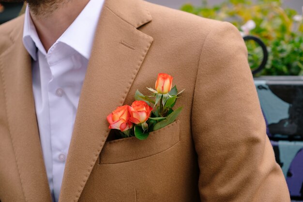 Nahaufnahme Mann gekleidet in edlem jaket mit drei Rosen in poket