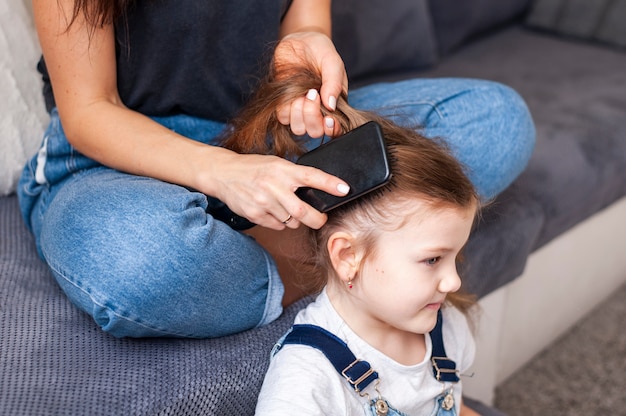 Nahaufnahme Mutter, die die Haare ihrer Töchter stylt