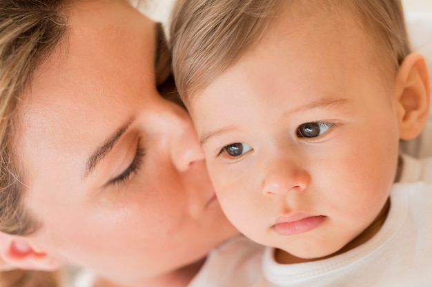 Nahaufnahme Mutter küsst Babys Wange