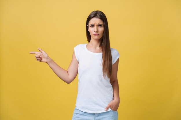 Nahaufnahme Porträt einer jungen, ziemlich unglücklichen, ernsthaften Frau, die auf jemanden zeigt, als ob Sie sagen wollten, dass Sie etwas falsch gemacht haben, einen schlechten Fehler, der auf gelbem Hintergrund isoliert ist. Negatives Gefühl im Gesichtsausdruck